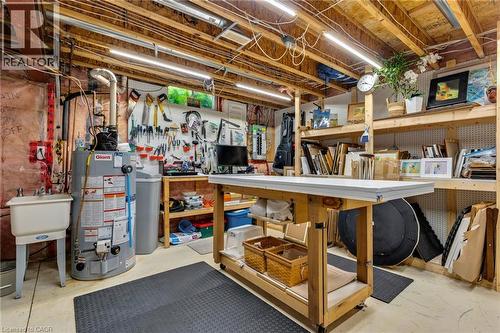 Utility room featuring exposed ceiling joists, overhead strip lighting, a utility sink, a hot water heater, and a water softener system - 350 Doon Valley Drive Unit# 6D, Kitchener, ON - Indoor Photo Showing Basement
