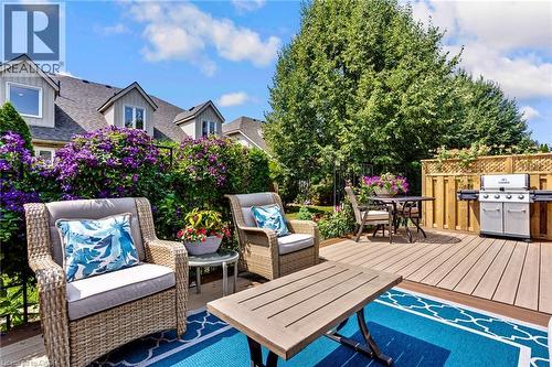Expansive outdoor deck featuring wood-finish decking, surrounded by vibrant purple flowering shrubs and mature trees - 350 Doon Valley Drive Unit# 6D, Kitchener, ON - Outdoor With Deck Patio Veranda