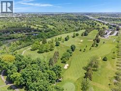 Expansive aerial capturing a manicured golf course with multiple greens, sand traps, and mature trees - 