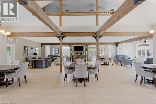 Spacious common area featuring vaulted ceilings with exposed wood beams, neutral tile flooring, a built-in fireplace, and large windows providing ample natural light - 350 Doon Valley Drive Unit# 6D, Kitchener, ON - Indoor Photo Showing Dining Room