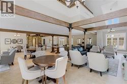 Spacious communal area featuring exposed wood-finish beams, vaulted ceilings, and light tile flooring - 