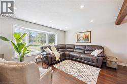 Bay window with white blinds, wood-finish flooring, recessed lighting, and a prominent wood beam accent - 
