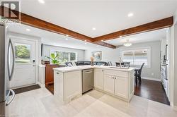 Modern kitchen featuring white cabinetry, a stainless steel dishwasher, and light tile flooring - 