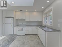 Kitchen featuring white cabinetry, grey granite-style countertops, double basin sink, and recessed lighting - 