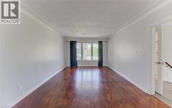 Spacious room featuring hardwood flooring, white walls, and a large front window - 