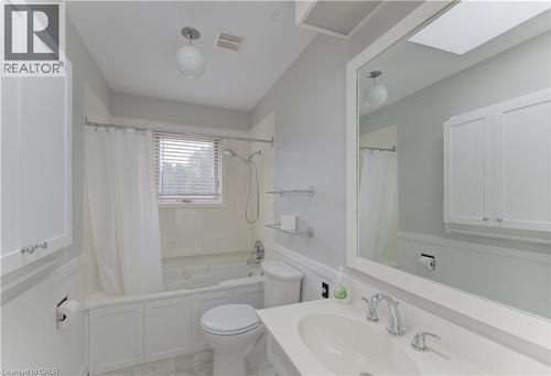 Bathroom featuring a combination tub/shower with white subway tile surround, white vanity cabinetry, a rectangular vanity mirror, and a skylight - 139 Trafalgar Avenue, Kitchener, ON - Indoor Photo Showing Bathroom