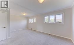 Spacious primary Bedroom featuring light gray carpet flooring, neutral painted walls, and white crown molding - 