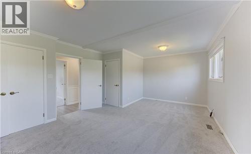 Spacious interior of primary bedroom featuring light gray carpeting, white walls, crown molding, and baseboards - 139 Trafalgar Avenue, Kitchener, ON - Indoor Photo Showing Other Room