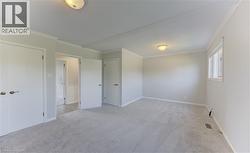 Spacious interior of primary bedroom featuring light gray carpeting, white walls, crown molding, and baseboards - 
