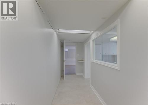 Hallway featuring light-colored walls and flooring, a ceiling-mounted light fixture, and a framed interior window - 139 Trafalgar Avenue, Kitchener, ON - Indoor Photo Showing Other Room