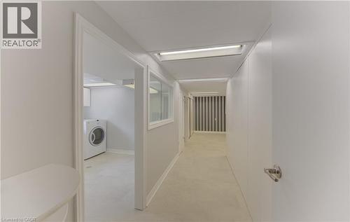 Corridor to laundry, utility, bathroom and walkout to yard featuring light-toned flooring, recessed lighting, and a view into a laundry area with a front-load washer - 139 Trafalgar Avenue, Kitchener, ON - Indoor Photo Showing Laundry Room