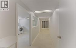 Corridor to laundry, utility, bathroom and walkout to yard featuring light-toned flooring, recessed lighting, and a view into a laundry area with a front-load washer - 