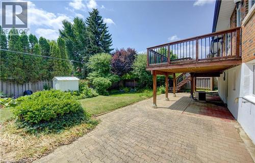 Expansive backyard featuring a raised wooden deck with railings, a lower patio area with patterned pavers, a manicured lawn, and mature perimeter trees - 139 Trafalgar Avenue, Kitchener, ON - Outdoor