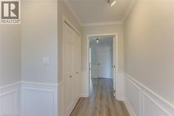 Hallway featuring wainscoting, crown molding, wood-finish flooring, bi-fold closet doors, and recessed lighting - 