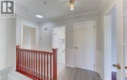 Hallway featuring wood-finish flooring, white paneling, and crown molding - 