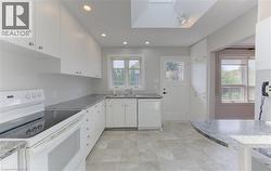 White cabinetry with granite-style countertops, an electric range, and a built-in dishwasher - 