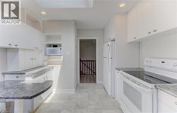 Kitchen featuring white cabinetry, gray patterned countertops, and a white electric range - 