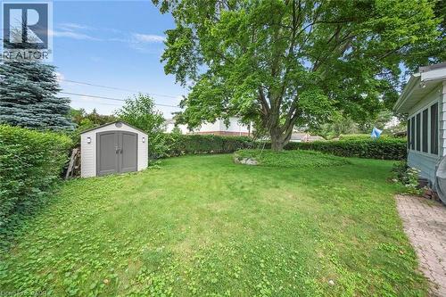 Expansive rear yard featuring mature trees, a manicured lawn, and a contemporary storage shed with dual gray doors and exterior lighting - 1063 Joan Drive, Burlington, ON - Outdoor