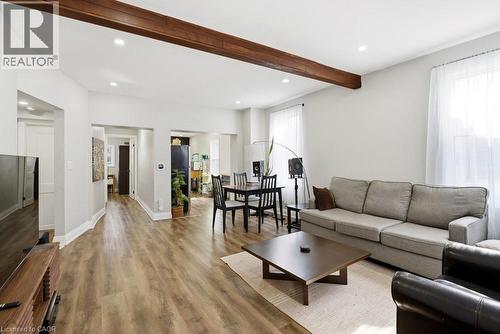Light-filled living area featuring wood-finish flooring, a prominent ceiling beam, recessed lighting, and multiple windows - 773 Lawrence Road, Hamilton, ON - Indoor Photo Showing Living Room