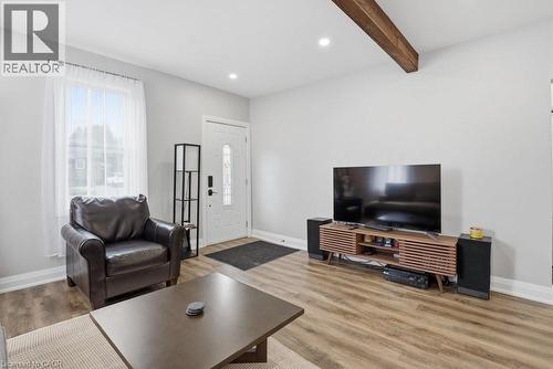 Living area featuring wood-finish flooring, recessed lighting, a prominent exposed wood beam, a white paneled entry door with decorative glass, and a large window providing natural light - 773 Lawrence Road, Hamilton, ON - Indoor Photo Showing Living Room