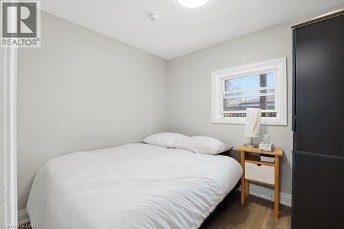 Compact room featuring light gray walls, wood-finish flooring, a white-trimmed window, a flush-mount ceiling light, and a dark built-in wardrobe - 773 Lawrence Road, Hamilton, ON - Indoor Photo Showing Bedroom