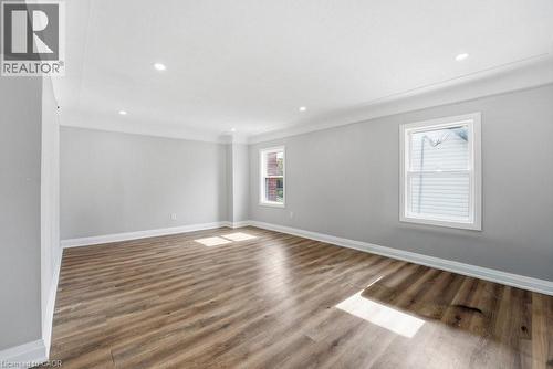 Spacious room featuring wood-finish flooring, light grey walls, recessed ceiling lighting, crown molding, and two windows with white trim - 773 Lawrence Road, Hamilton, ON - Indoor Photo Showing Other Room