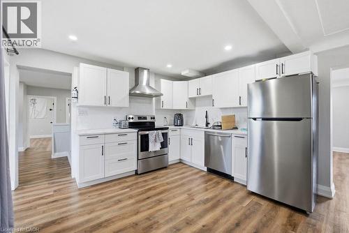 Kitchen featuring wood-finish flooring, white cabinetry with dark hardware, stainless steel appliances, a tile backsplash, and recessed lighting - 773 Lawrence Road, Hamilton, ON - Indoor Photo Showing Kitchen