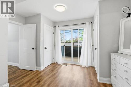 Wood-finish flooring throughout, featuring a sliding glass door providing natural light and access to a deck with dark railing - 773 Lawrence Road, Hamilton, ON - Indoor Photo Showing Other Room
