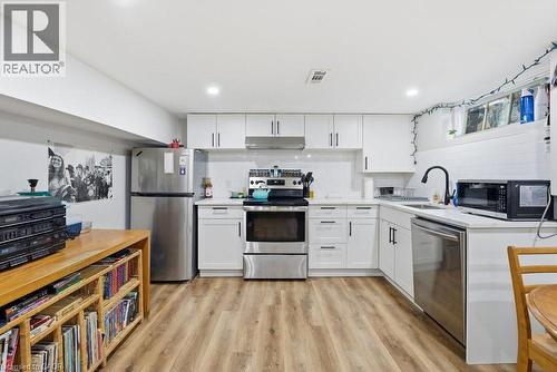 Modern kitchen featuring white cabinetry, stainless steel appliances, wood-finish flooring, white subway tile backsplash, and recessed lighting - 773 Lawrence Road, Hamilton, ON - Indoor Photo Showing Kitchen