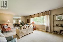 Spacious living area featuring a large picture window, a built-in fireplace with a mirrored surround, and wall-to-wall carpeting - 