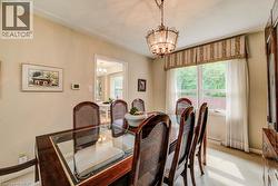 Dining area featuring a decorative chandelier, crown molding, and a large window with privacy sheers - 