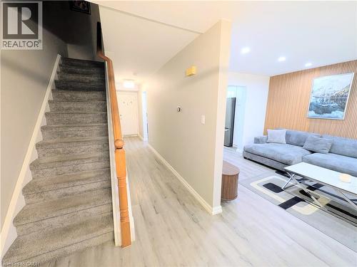 Entryway featuring light wood-finish flooring extending into a spacious living area with a decorative wood-slat accent wall - 22 Riverdale Drive Unit# 1, Hamilton, ON - Indoor
