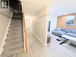Entryway featuring light wood-finish flooring extending into a spacious living area with a decorative wood-slat accent wall - 