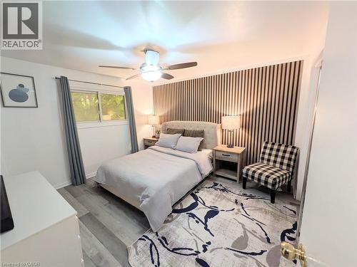 Interior space featuring wood-finish flooring, a contemporary ceiling fan with integrated lighting, and a window with gray drapes - 22 Riverdale Drive Unit# 1, Hamilton, ON - Indoor Photo Showing Bedroom
