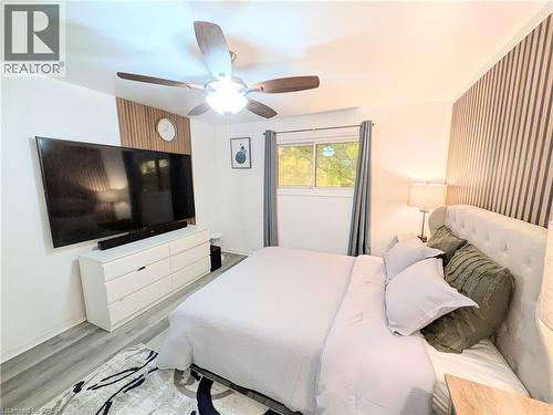 Bedroom featuring wood-finish flooring, a ceiling fan with integrated lighting, and a window with drapes - 22 Riverdale Drive Unit# 1, Hamilton, ON - Indoor Photo Showing Bedroom