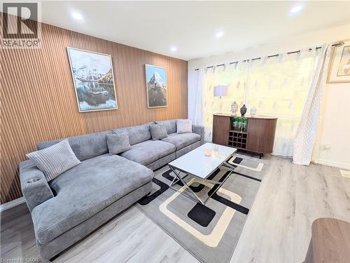 Living space featuring a wood-panel accent wall, recessed lighting, light wood-finish flooring, and a window with sheer curtains - 22 Riverdale Drive Unit# 1, Hamilton, ON - Indoor Photo Showing Living Room