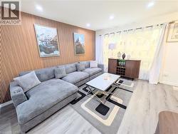 Living space featuring a wood-panel accent wall, recessed lighting, light wood-finish flooring, and a window with sheer curtains - 