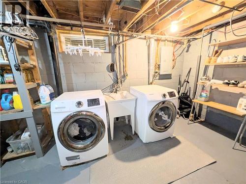 Dedicated laundry area featuring a utility sink, two front-loading laundry machines, block wall construction, and exposed ceiling joists - 22 Riverdale Drive Unit# 1, Hamilton, ON - Indoor Photo Showing Laundry Room