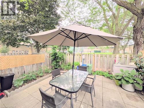 Private patio area featuring paver flooring, a perimeter fence with lattice accents, and mature trees providing shade - 22 Riverdale Drive Unit# 1, Hamilton, ON - Outdoor With Deck Patio Veranda