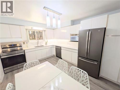Contemporary kitchen featuring white cabinetry, light-toned countertops, and wood-finish flooring - 22 Riverdale Drive Unit# 1, Hamilton, ON - Indoor Photo Showing Kitchen With Stainless Steel Kitchen