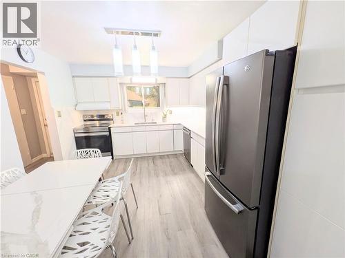 Modern kitchen featuring white cabinetry, light-toned wood-finish flooring, and sleek stainless steel appliances - 22 Riverdale Drive Unit# 1, Hamilton, ON - Indoor Photo Showing Kitchen With Stainless Steel Kitchen
