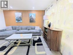 Living area featuring an accent wall with wood paneling, recessed lighting, and a patterned area rug - 