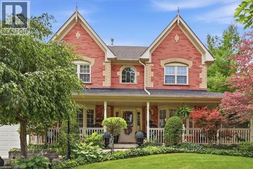 Red brick facade featuring gabled rooflines, contrasting brick accents, and a covered porch with white railings - 39 Everwood Run, Kitchener, ON - Outdoor With Deck Patio Veranda