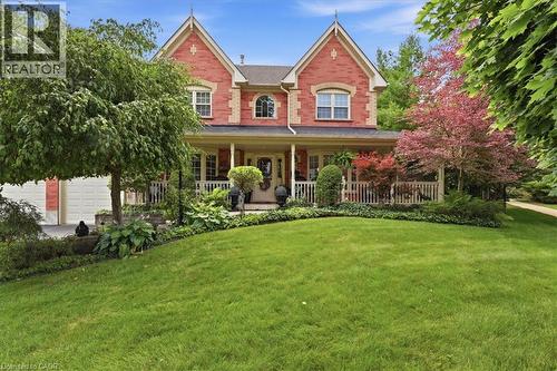Brick exterior featuring gabled rooflines, a covered front porch with white railings, a two-car garage, and established landscaping - 39 Everwood Run, Kitchener, ON - Outdoor With Deck Patio Veranda