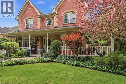 Brick facade residence featuring a covered front porch, white railing, and decorative arched window - 39 Everwood Run, Kitchener, ON - Outdoor With Deck Patio Veranda