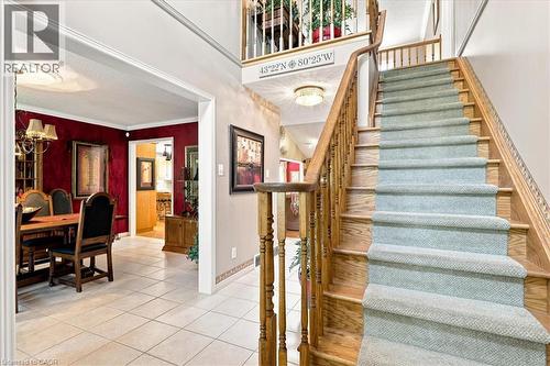 Two-story foyer featuring a wood staircase with carpet runner, tile flooring, and a formal dining room with deep red walls - 39 Everwood Run, Kitchener, ON - Indoor Photo Showing Other Room
