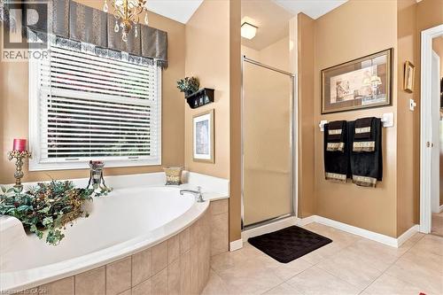Soaking tub with a tiled surround, framed window with blinds, and an overhead valance - 39 Everwood Run, Kitchener, ON - Indoor Photo Showing Bathroom