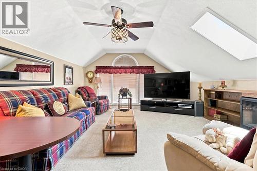 Vaulted ceiling bonus room featuring a skylight, ceiling fan with integrated lighting, arched window, built-in shelving, and carpeted flooring - 39 Everwood Run, Kitchener, ON - Indoor Photo Showing Living Room With Fireplace
