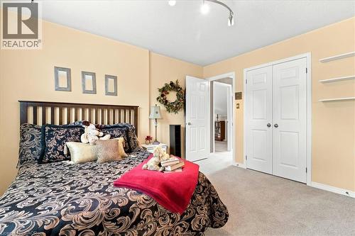 Bedroom featuring carpet flooring, built-in shelving, white paneled bifold closet doors, and a wood-slat headboard - 39 Everwood Run, Kitchener, ON - Indoor Photo Showing Bedroom