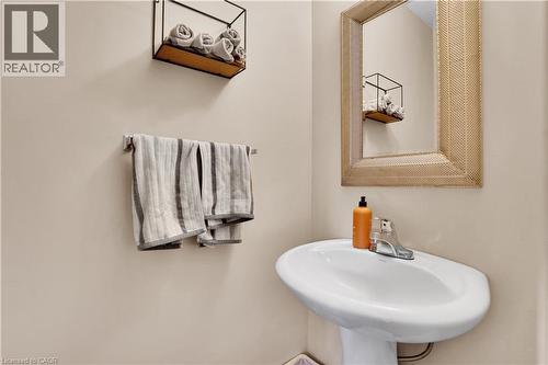 Pedestal sink with chrome faucet, framed mirror, and wall-mounted metal and wood-finish shelving - 60 Featherstone Street, Kitchener, ON - Indoor Photo Showing Bathroom